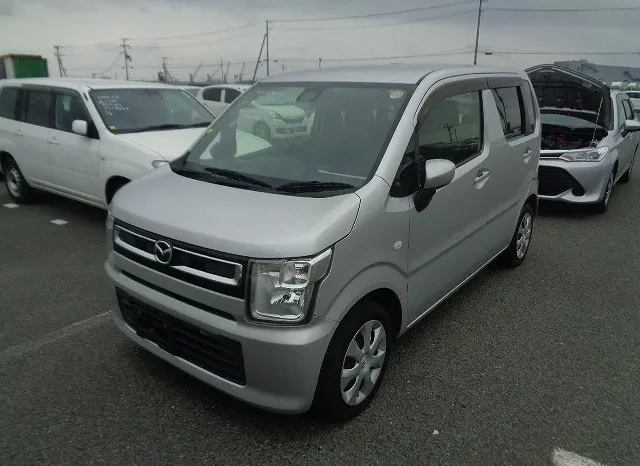 A Silver Compact Van, Perfect For Any Car Sale Enthusiast, Is Parked In A Lot On A Cloudy Day. Several Other Vehicles Can Be Seen In The Background. This Boxy-Shaped Van Is Facing The Camera, Embodying Quality That Would Thrive At Mundiya Best Car Sale Events In Kenya.