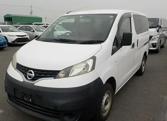 White Nissan Nv200 Van Parked In A Lot, Surrounded By Other Vehicles, Possibly From Mundiya Best Car Dealer. The Van Features A Black Front Bumper And Silver Wheels Under An Overcast Sky.